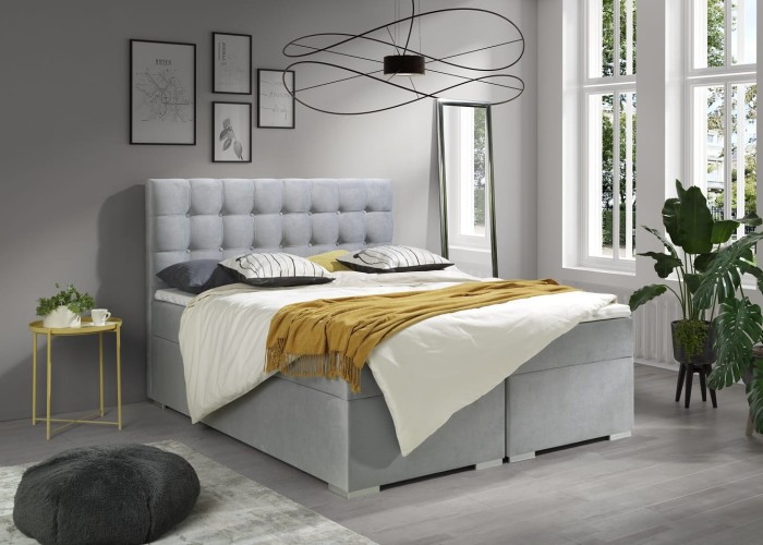 Modernes hellgraues Boxspringbett mit gestepptem Kopfteil im Schlafzimmer.