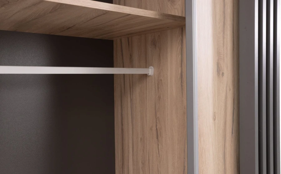 Detailansicht des Kleiderschrank-Innenraums mit Kleiderstange und Regalboden.