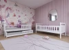 Weißes Kinderbett mit Ausziehbett in rosa Mädchenzimmer mit Blumen-Tapete.