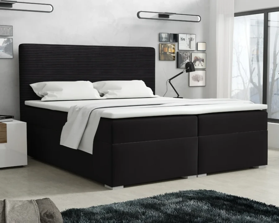 Elegantes schwarzes Boxspringbett mit gepolstertem Kopfteil und weißer Bettwäsche.