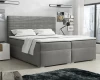 Graues Boxspringbett mit markantem Rillen-Kopfteil in einem hellen Schlafzimmer-Ambiente.