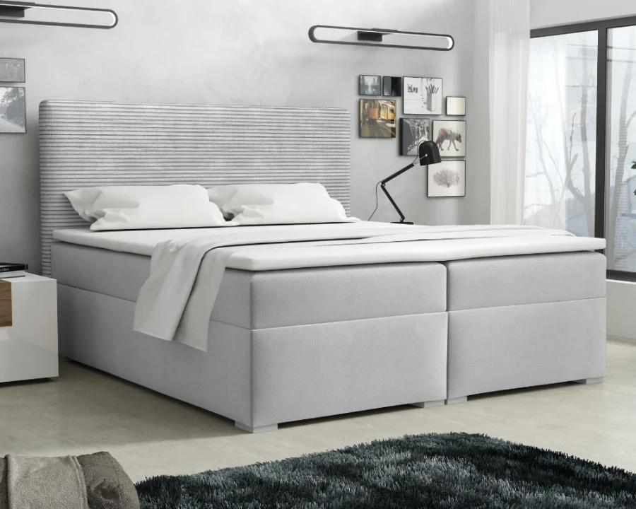 Hellgraues Boxspringbett mit modernem gestreiftem Kopfteil in gemütlicher Schlafzimmer-Umgebung.