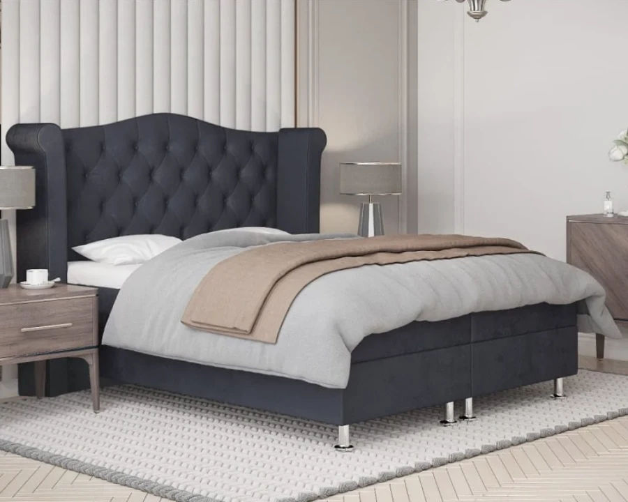 Seitenansicht eines gemütlichen grauen Boxspringbetts in einem stilvoll eingerichteten Schlafzimmer.