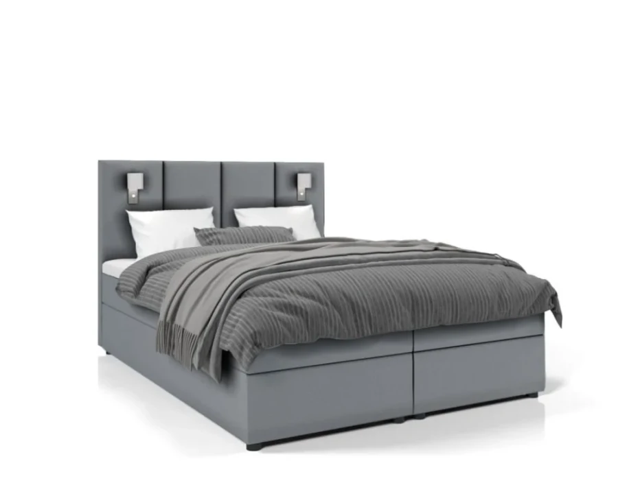 Graues Boxspringbett mit gepolstertem Kopfteil und Leselampen auf weißem Hintergrund.