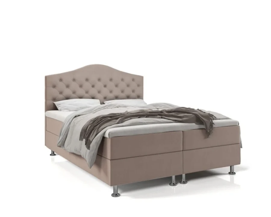 Beiges Boxspringbett mit gepolstertem Kopfteil und silbernen Füßen.