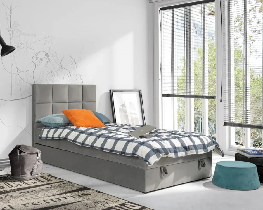 Modernes graues Polsterbett für das Jugendzimmer mit karierter Bettwäsche.