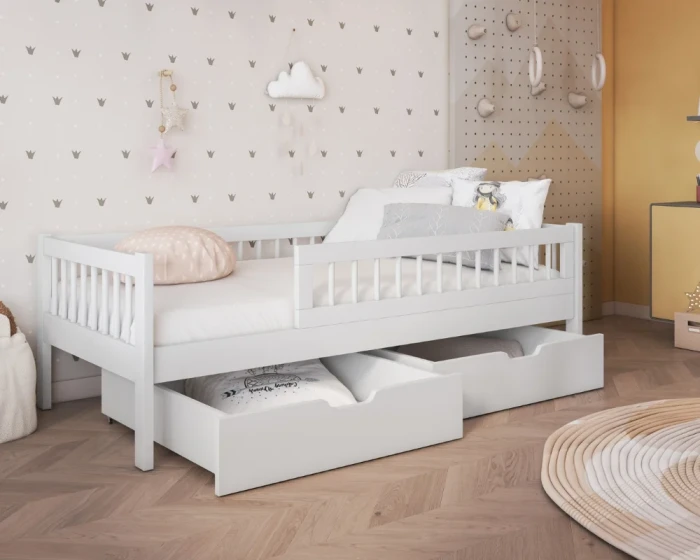 Weißes Kinderbett aus Kiefernholz mit Schubladen und Rausfallschutz im modernen Kinderzimmer.