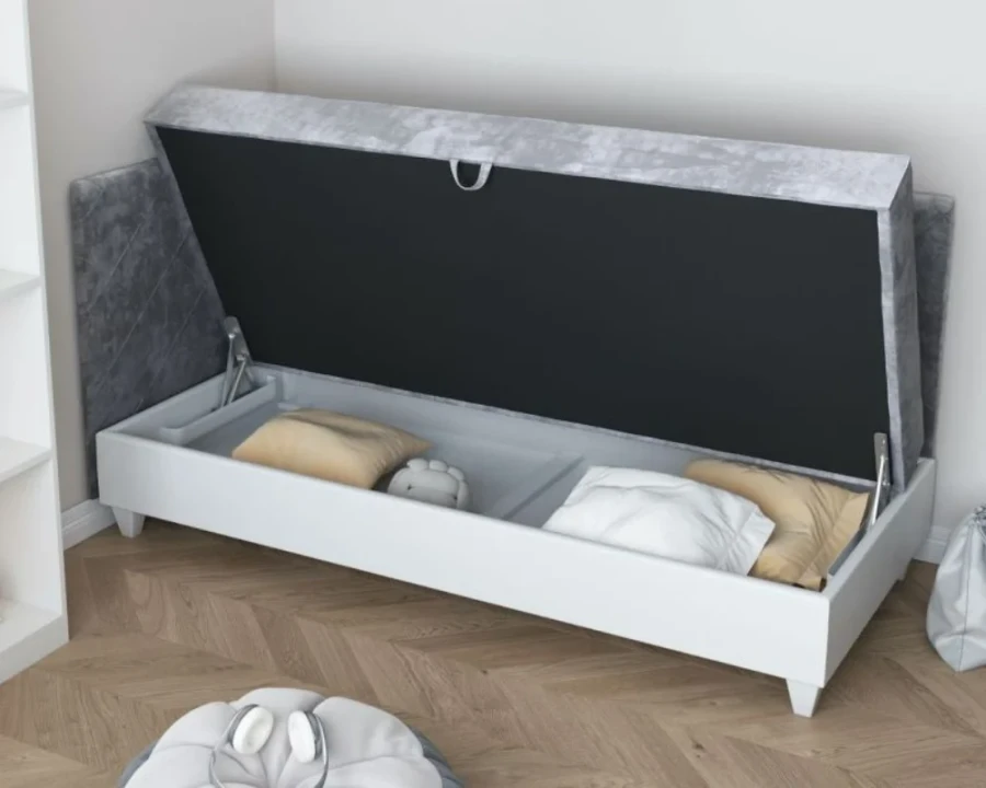 Graues Polsterbett mit offenem Bettkasten und weißem Gestell für extra Stauraum.