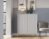 Elegantes weißes Highboard mit vertikalen Rillen und goldenen Füßen vor einer zweifarbigen Wand.