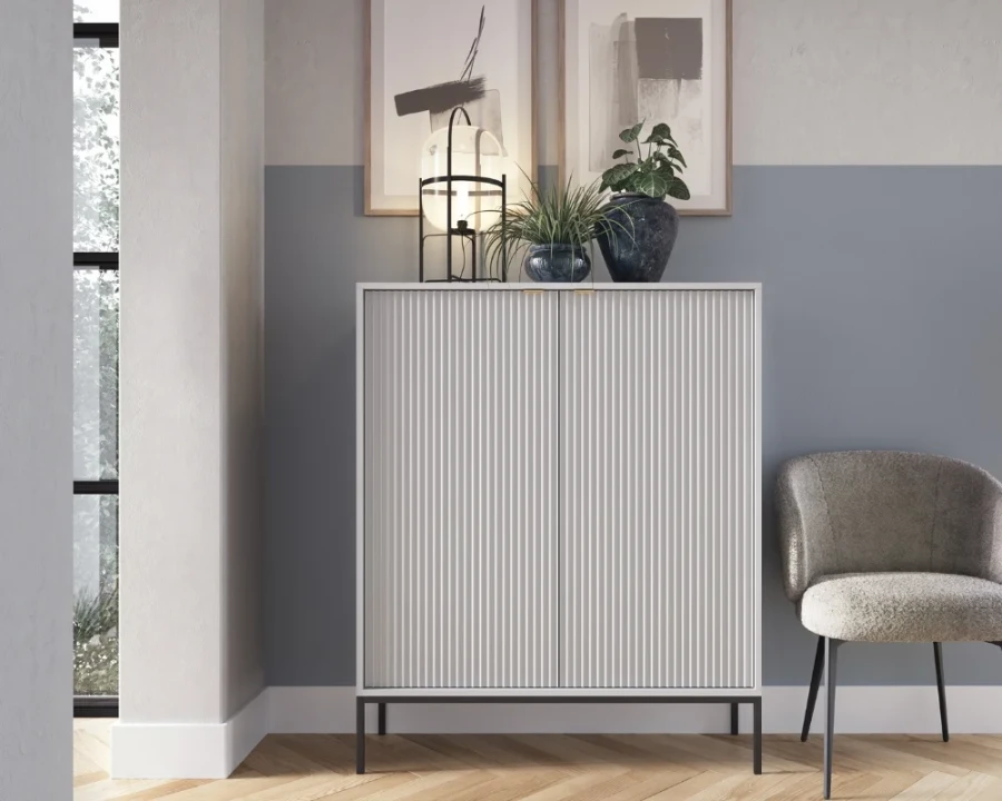 Modernes Highboard in Weiß mit schwarzen Metallfüßen und geriffelter Front für stilvolle Aufbewahrung.
