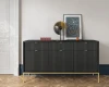 Elegante schwarze Kommode mit Riffelfront und goldenen Beinen in stilvollem Ambiente.