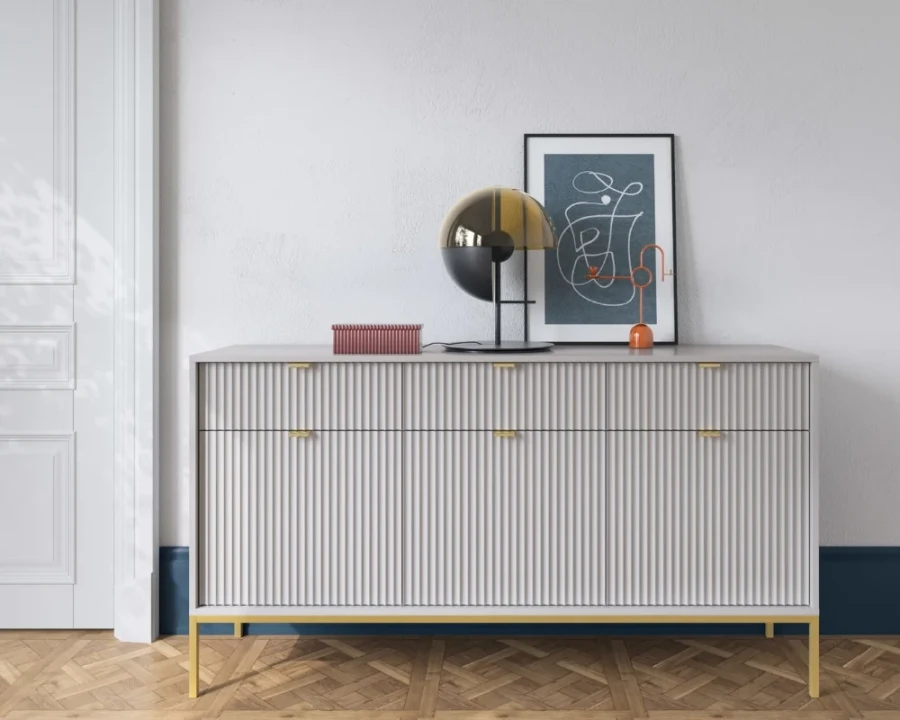 Elegantes graues Sideboard mit Riffelfront und goldenen Beinen in modernem Ambiente.