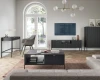 Modernes Wohnzimmer mit schwarzem Couchtisch, TV-Board und Schreibtisch mit schwarzen Beinen.