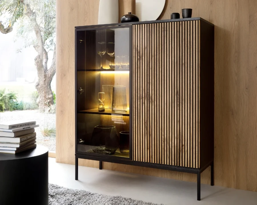 Modernes Sentio Highboard im Wohnzimmer mit Lamellenoptik, Glasfront und stimmungsvoller LED-Beleuchtung.