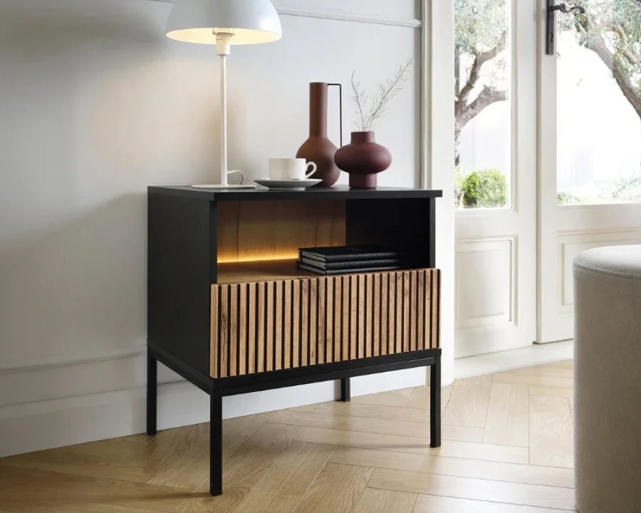 Modern eingerichtetes Schlafzimmer mit Nachtschrank, Designerlampe und Deko auf hellem Eichenparkett.