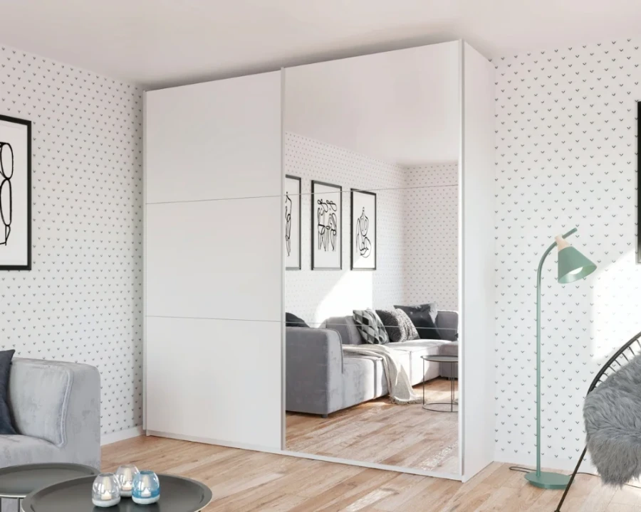 Weißer Schwebetürenschrank mit großer Spiegelfront in hellem Zimmer.
