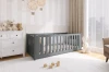 Modernes Kinderzimmer mit grauem Gitterbett, weißer Kommode und liebevoller Dekoration.