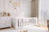 Stilvolles weißes Kinderbett im Zimmer mit gestreifter Tapete, Plüschtieren und Heißluftballons.