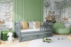 Stilvolles Kinderzimmer mit grauem Ausziehbett, Waldmotiven und grüner Wandpaneele.