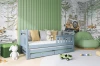 Hellblaues Ausziehbett in einem modernen Kinderzimmer mit Waldmotiv-Tapete und Kuscheltieren.