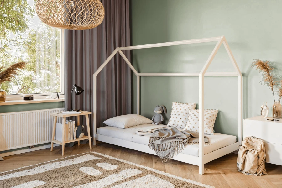 Stilvolles Kinderzimmer-Interieur mit weißem Hausbett, gemütlichem Teppich und Deko.