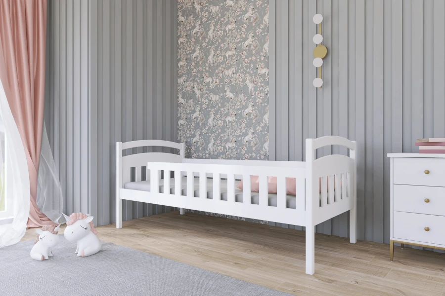 Niedriges weißes Kinderbett mit Seitenschutz in einem hellen Zimmer mit Einhorn-Deko.