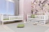 Wit kinderbed van hout met uitschuifbed en laden in een moderne kinderkamer.