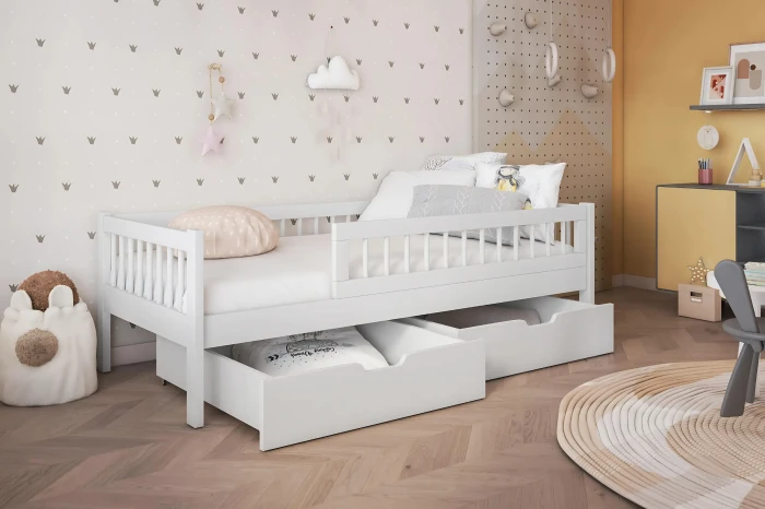 Weißes Kinderbett aus Massivholz mit zwei Bettschubladen und Rausfallschutz im hellen Kinderzimmer.
