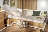 Gemütliches Kinderbett aus hellem Holz mit Kissen, Kuscheltieren und einer sternförmigen Lampe.