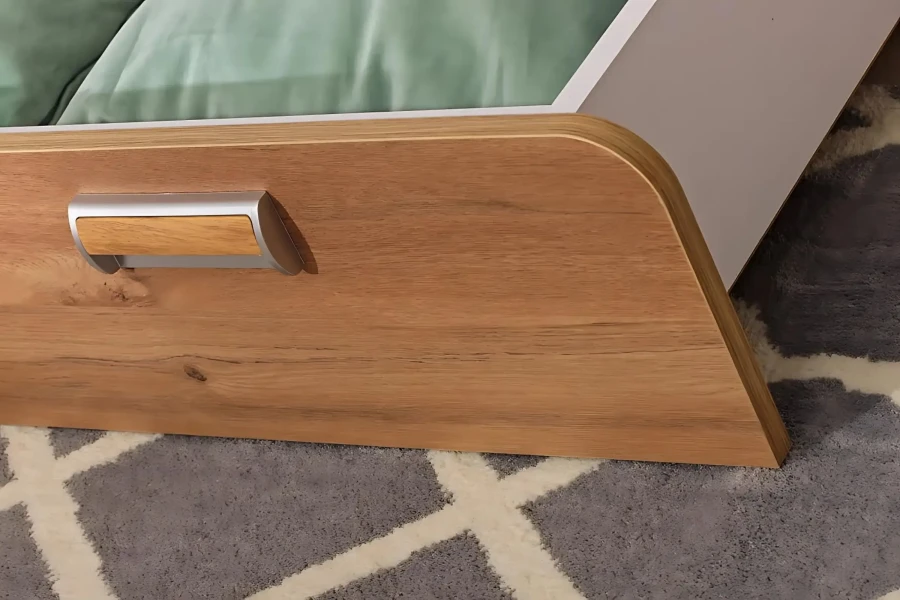 Nahaufnahme der hochwertigen Holzoptik und des modernen Griffs einer Bettschublade für Kinderbetten.