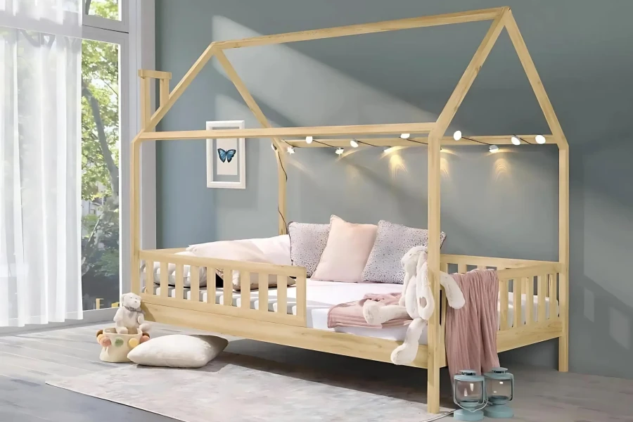 Gemütliches Kinderhausbett aus Kiefernholz mit Lichterkette und Kissen dekoriert.