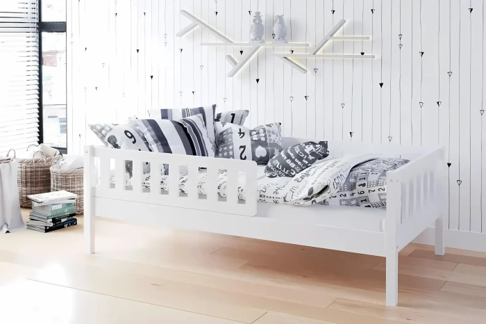 Modern wit kinderbed in Scandinavische stijl met uitvalbeveiliging en sierkussens.