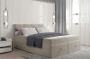 Beiges Boxspringbett in modernem Schlafzimmer-Ambiente mit dekorativer Bettwäsche.