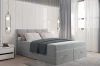 Hellgraues Boxspringbett dekoriert mit Kissen und Decke für gemütliche Atmosphäre.