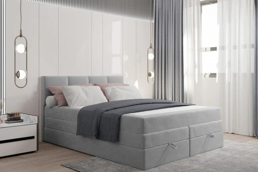 Hellgraues Boxspringbett dekoriert mit Kissen und Decke für gemütliche Atmosphäre.