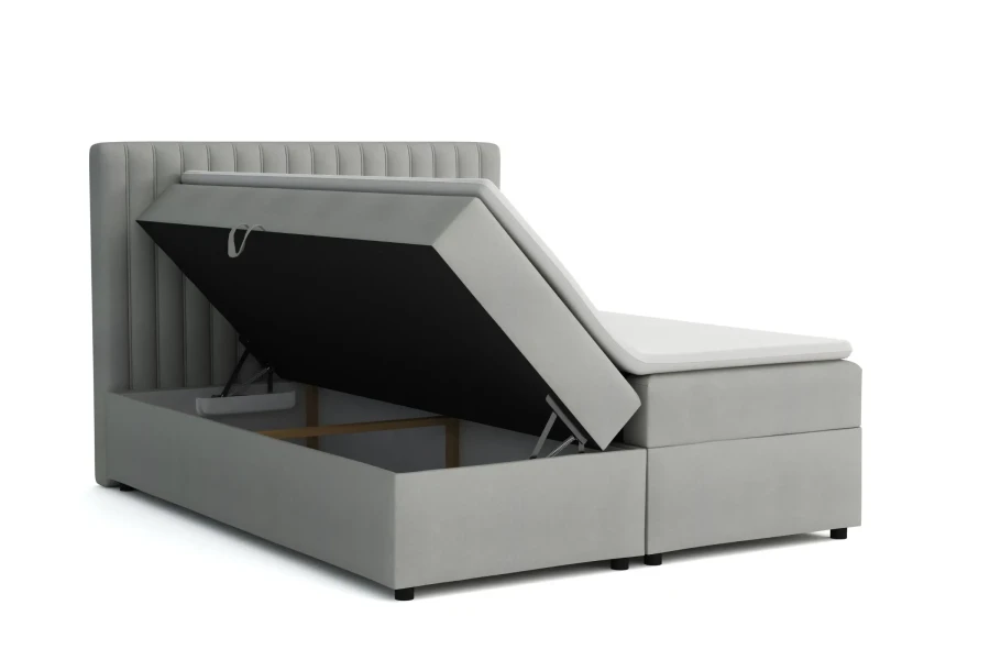 Hellgraues Boxspringbett mit geöffnetem Bettkasten und Stauraum.
