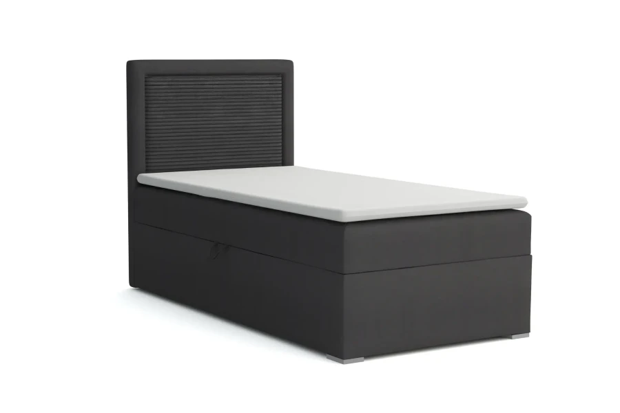 Schwarzes Boxspringbett mit geriffeltem Kopfteil und weißem Topper auf weißem Grund.