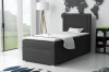 Stilvolles schwarzes Boxspringbett in hellem Raum mit Bücherregal und Fenster.