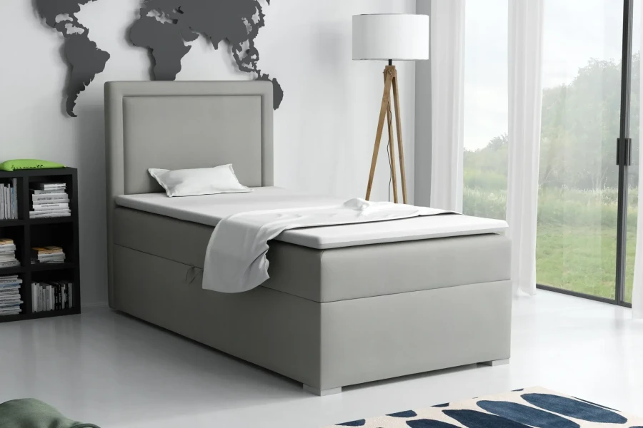 Graues Boxspringbett Einzelbett in hell eingerichteter Schlafzimmerumgebung.