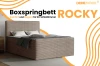Beiges Boxspringbett Rocky im Schlafzimmer-Ambiente für Komfort und Eleganz.