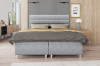 Frontalansicht eines modernen grauen Boxspringbettes in wohnlicher Atmosphäre.
