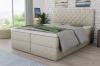 Elegantes Boxspringbett in Beige mit Kristallen am Kopfteil in einem hellen Schlafzimmer.