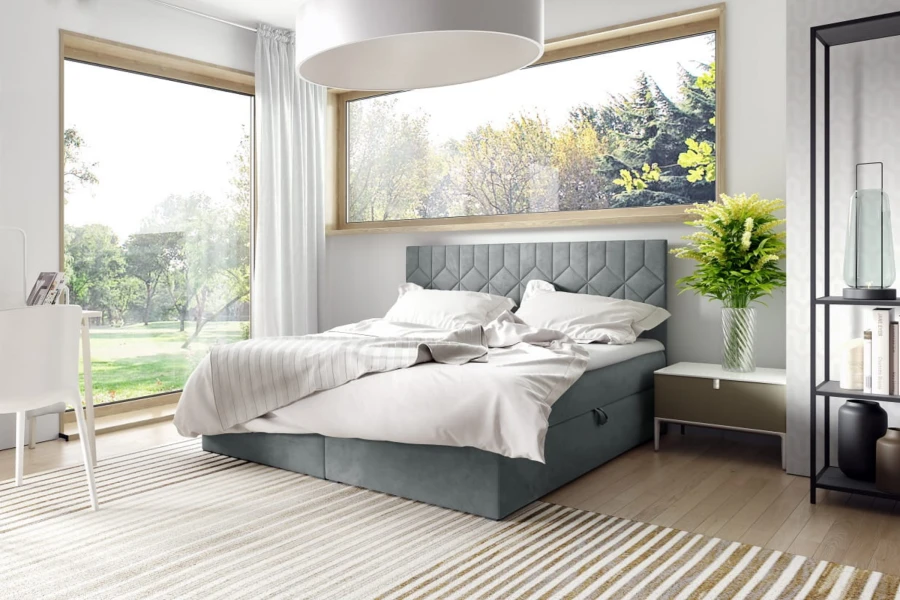 Modernes blaues Boxspringbett in hellem Schlafzimmer mit großem Fenster zum Garten.
