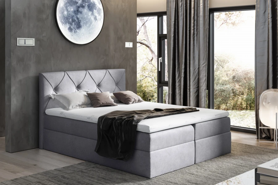 Hellgraues Boxspringbett mit gestepptem Kopfteil in modernem Ambiente.