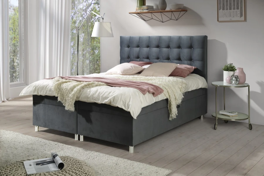 Modernes Polsterbett in Grau mit gestepptem Kopfteil in einem hellen Schlafzimmer.