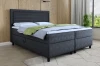 Modern boxspringbed in donkergrijs met hoog hoofdbord en gezellig beddengoed in de slaapkamer.