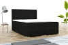 Elegant zwart boxspringbed met witte topper in een moderne kamer met designlamp en plant.