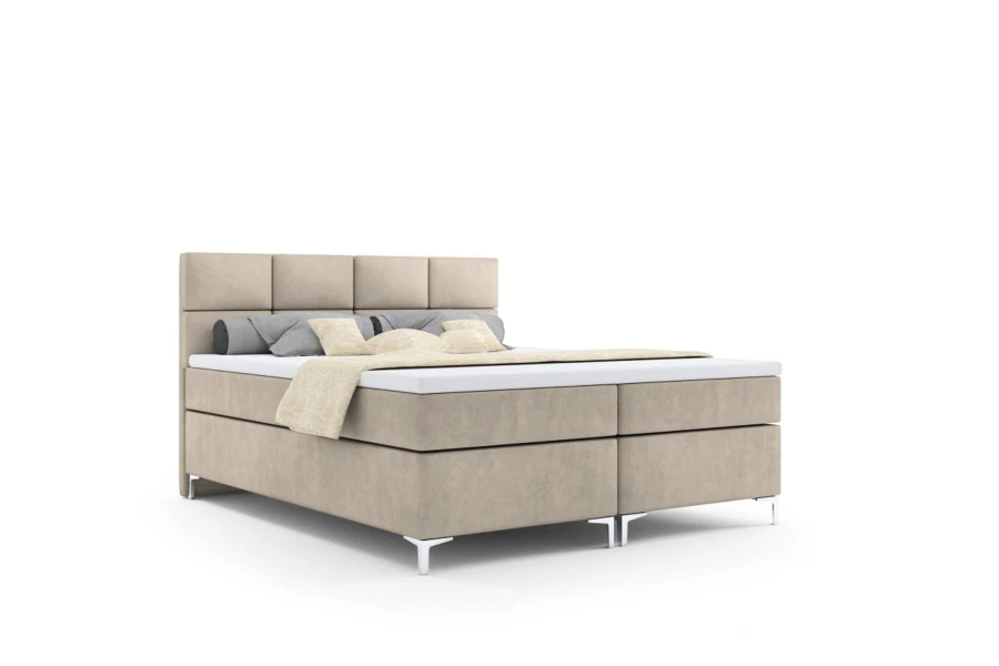 Beige boxspringbed met gestoffeerd hoofdbord vrijstaand voor een witte achtergrond.