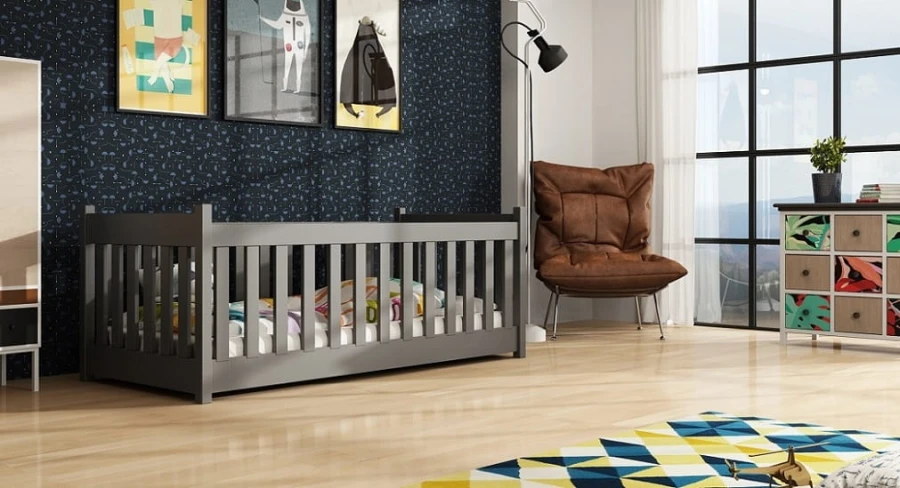 Modernes graues Kinderbett mit Rausfallschutz vor einer dunklen Motivtapete.