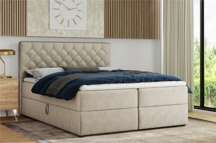 Modern beige boxspringbed met gecapitonneerd hoofdbord in een ingerichte kamer.